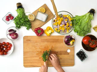 healthy eating, vegetarian food and cooking concept - POV shot of hands with knife chopping parsley on wooden cutting board for salad at kitchen