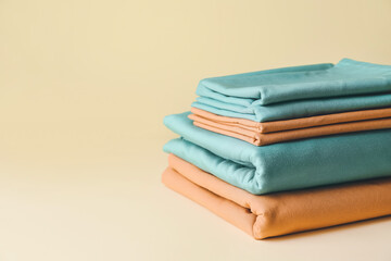 Stack of clean bed sheets on color background