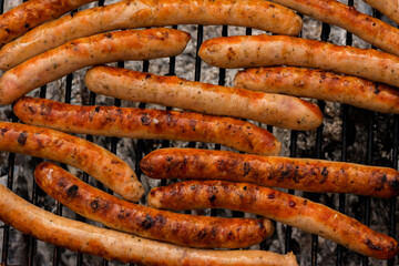 Meat sausages, bratwurst on a barbecue rack. Outdoor grill on a summer weekend. Picnic with grilled meat