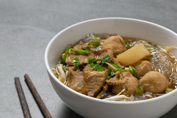 Vermicelli with beef in white bowl on concrete table.