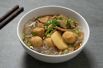 Vermicelli with beef in white bowl on concrete table.