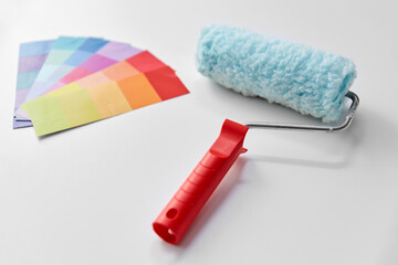 repair, renovation and painting concept - paint brush and color roller on white background
