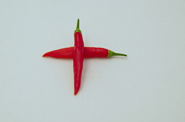 Sign or symbol addition or plus, made from the fruit of fresh chilli red pepper with a green stalk,...