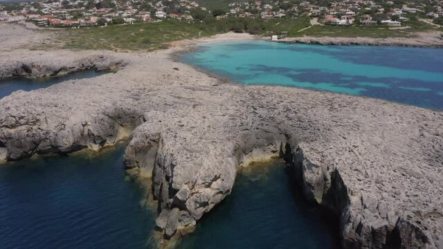 Empty Rocky Coast Of Binibeca Beach During The Coronavirus Outbreak In Menorca, Balearic Islands, Spain On A Sunny day. - aerial drone
