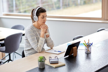 remote job, technology and people concept - young woman in headphones with tablet pc computer working at home office