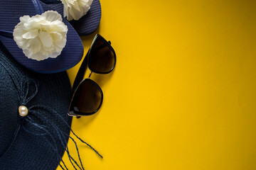 Obraz na płótnie Canvas Summer beach women hat, flip flops and sunglasses on yellow background. Summertime concept