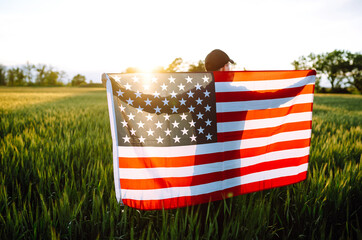 Fourth of July. Patriotic man with the national American flag in the field. Young man proudly...
