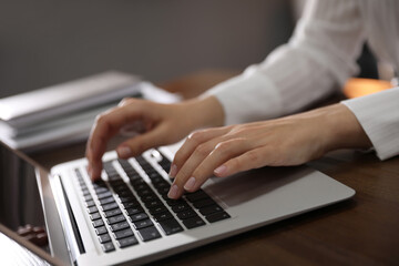 Woman working with laptop in office, closeup of hands