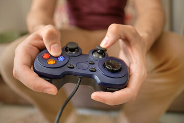 Excited young handsome man playing video game while sitting on the couch at home. Hand hold joystick. Gamer play game with gamepad controller. Gaming man holding simulator joypad. 