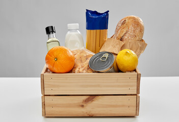 eating, grocery and delivery concept - food in wooden box on table over grey background