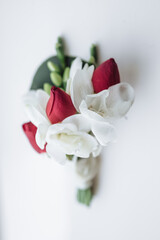 Wedding boutonniere of the groom with white and red flowers