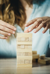 girl stacks a tower of wooden bricks at the table close-up