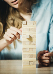 girl stacks a tower of wooden bricks at the table close-up