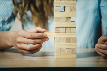 girl stacks a tower of wooden bricks at the table close-up