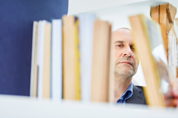 Mann als Leser oder Bibliothekar sortiert Bücher