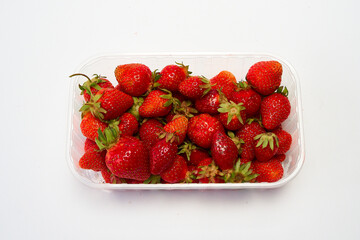 Tray of ripe red strawberries on a white background.