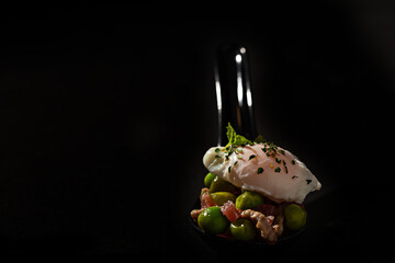 Spoonful of poached egg with peas, ham and red pepper