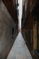 Fototapeta na wymiar An empty alley with brown brick walls in daylight Venice, Italy. Light at the end of the tunnel.