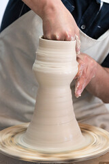 Potter sculpts from clay in a workshop of pots using ancient technology.