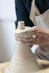 Potter sculpts from clay in a workshop of pots using ancient technology.