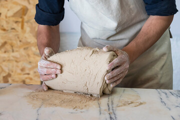 Potter sculpts from clay in a workshop of pots using ancient technology.