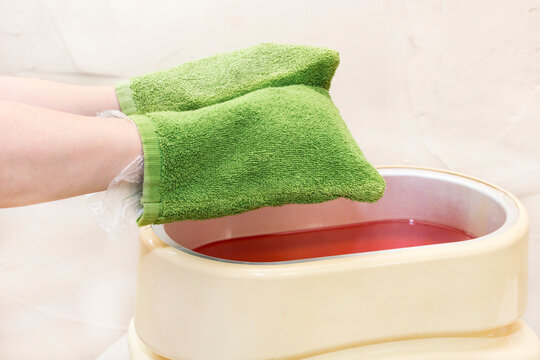 The process of paraffin therapy of a female hand is shot close up in a beauty salon.