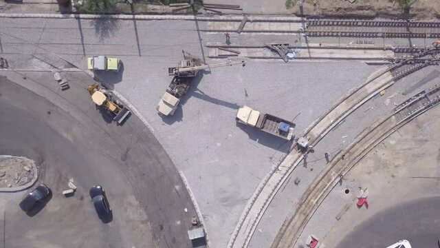 Work crane and truck on the construction of a road. Crushed stone on substrate. Support activities and reconstruction of tram tracks. Aerial view from drone