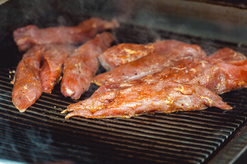 Raw chicken fillets on the metal grill