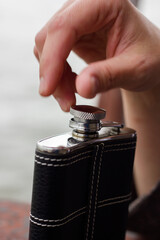 Hand holding a stainless steel hip flask for liquor, alcohol and drink concept close-up