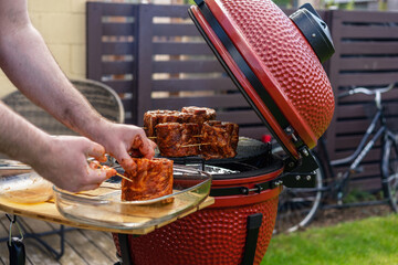 Red Ceramic Barbecue Grill. The man supervises the Grilling, Smoking, Baking, BBQ and Roasting process. Post-quarantine Picnic in modern homes terrace. 
