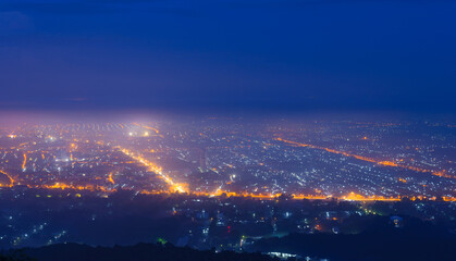 Illuminated city at foggy night