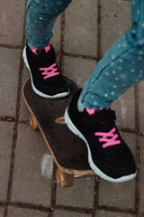 Children's feet on a skateboard, on the asphalt