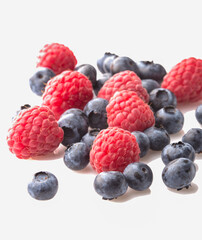 Ripe raspberries and blueberries on a white background