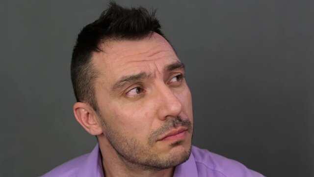 Pensive face of a young man close-up. He shows emotions. Professional acting. Soft light. High-quality footage FullHD. Video 1920x1080.