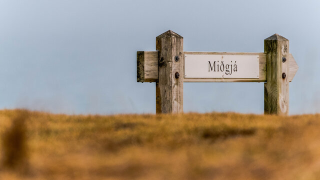 On the road above the cliffs at Arnastapi in western Iceland, a sign indicates how to get to the Midgja rift
