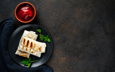 
Burritos wraps with chicken, mushrooms, and vegetables on a plate on a stone background. Delicious shawarma with copy space for your text.