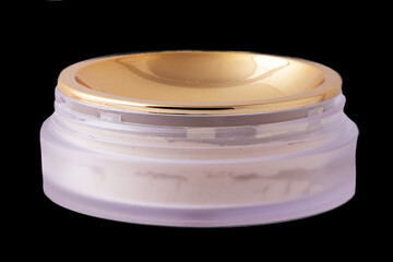 Cosmetic products isolated. Closeup of a elegant open jar with cheek or face powder. Make-up isolated on a black background. Macro from a blusher or bronzer.