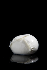 mozzarella cheese from Campania region Italy on a black mirrored background with cutting light