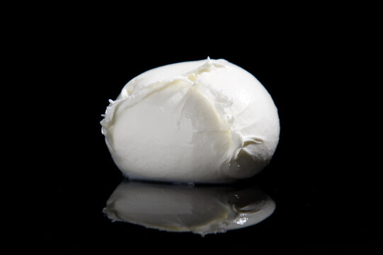 production buffalo mozzarella cheese from Campania region Italy on a black mirrored background with cutting light
