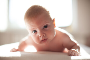 infant laying on the bed in the lights of sun