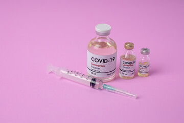 Coronavirus vaccination glass bottle on a pink background Covid-19 Vaccination Equipment Research on the concept of pandemic influenza vaccines around the world.