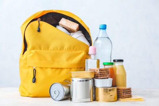 Schoolbag with different products on light background. Concept of Backpack Food Program