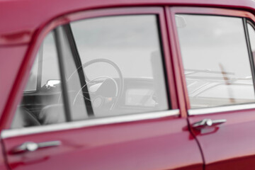 Interior of a red retro car. Transparent windows, thin steering wheel.