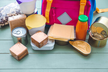 Schoolbag with different products on wooden background. Concept of Backpack Food Program
