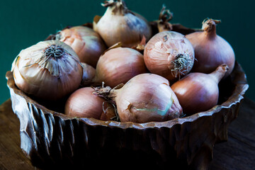 wooden bowl with onions on green background
