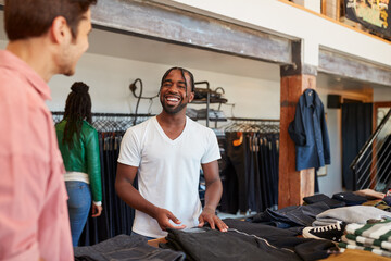 Smiling Sales Assistant Helping Male Customer To Buy Clothes In Fashion Store