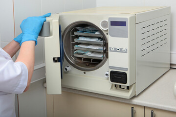 Cabinet for sterilization of dental instruments. The hands of an employee of the clinic latex...