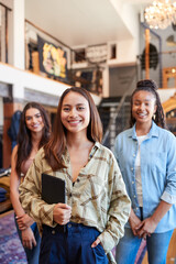 Portrait Of Smiling Multi-Cultural Female Sales Team In Fashion Store In Front Of Clothing Display