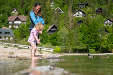 Mother and daughter exploring lake shore in summer.