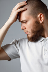 Portrait of a handsome young man looking upset to the side on gray background. isolated